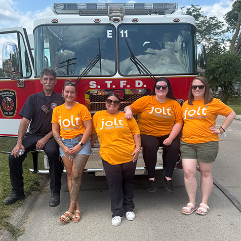 Jolt employees posing in front of Saginaw Township Fire Truck with Firefighter