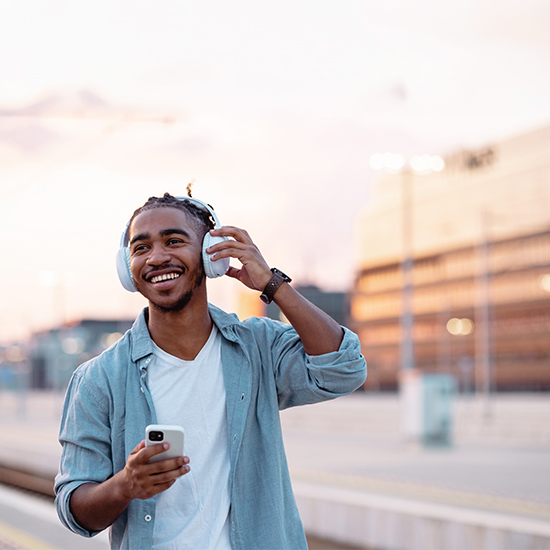 happy man walking with headphones and phone
