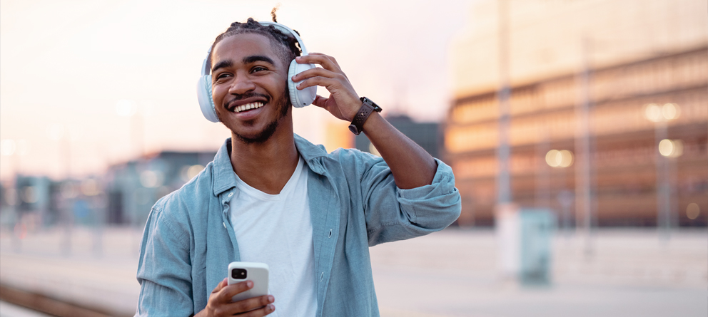 happy man walking with headphones and phone