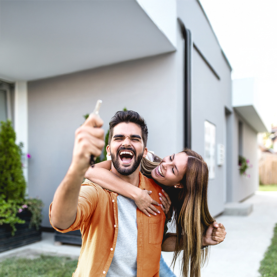 Excited couple holding keys, just bought a new house
