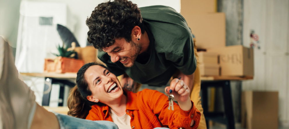 Excited couple holding keys, just bought a new house
