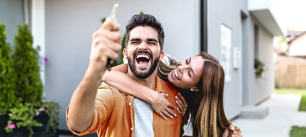 Excited couple holding keys, just bought a new house